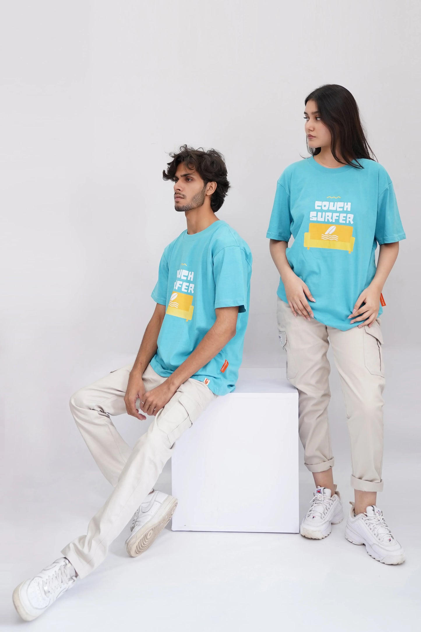 Two people wearing matching blue t-shirts with yellow accents on a white background
