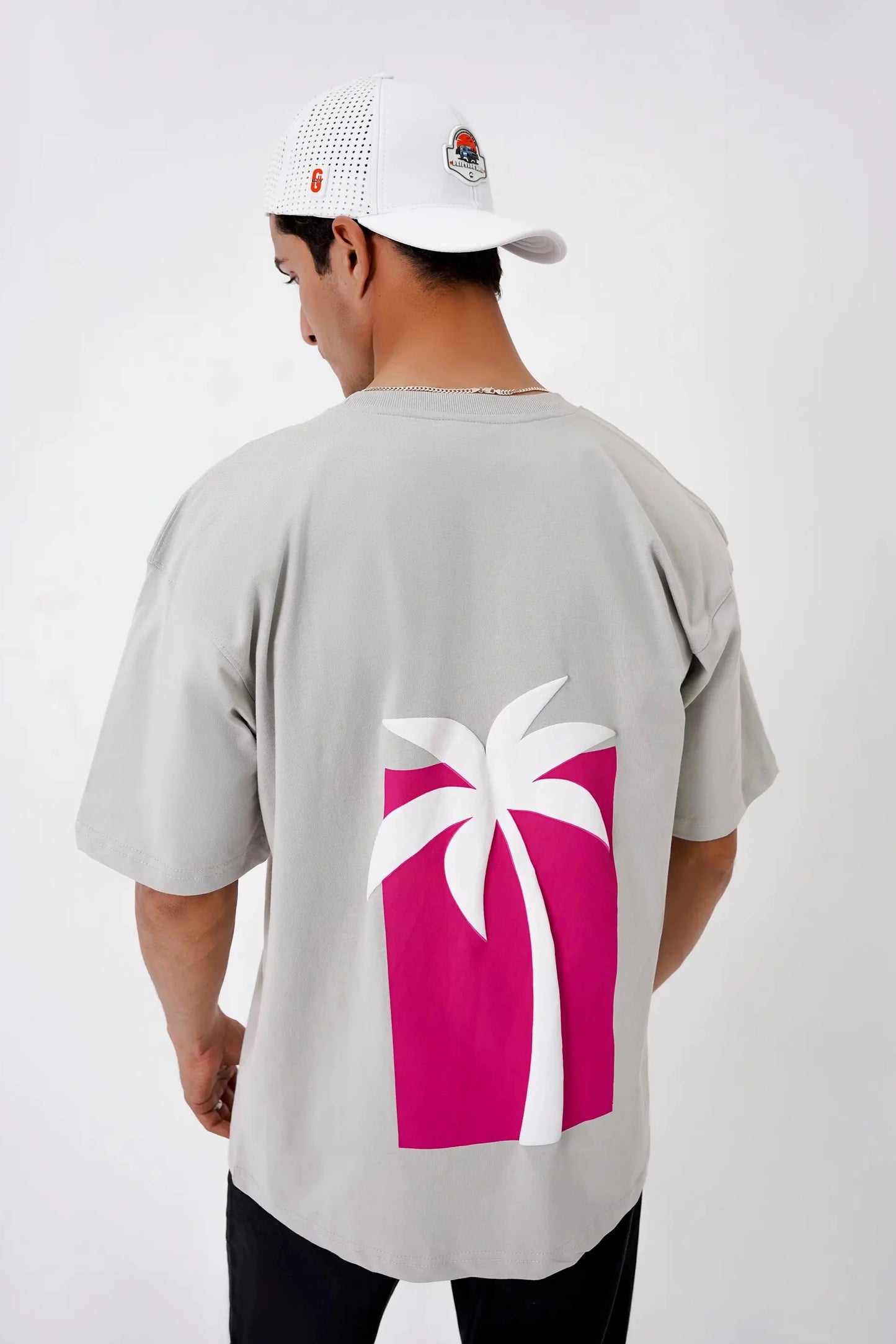 Person wearing a gray t-shirt with a pink palm tree design on a white background