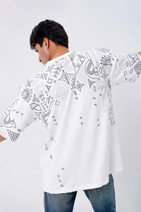 Person wearing a white shirt with black patterns on a plain background