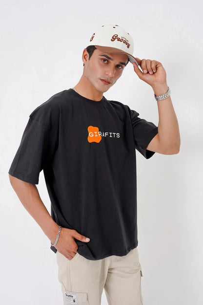 Person wearing a black t-shirt with a logo and text, beige pants, and a white cap on a white background