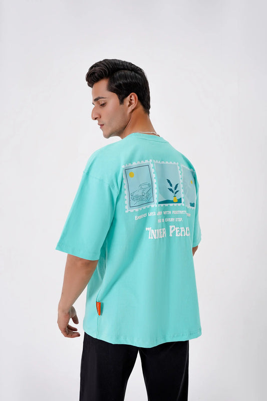 Person wearing a light green t-shirt with a graphic design on a white background